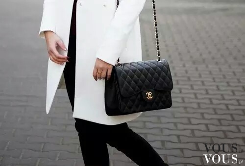Biały klasyczny płaszcz i czarna pikowana torebka Chanel na ramię.
