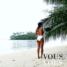 Zgrabna dziewczyna w białym bikini na plaży z palmami