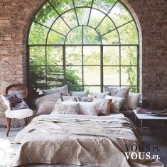 Piękna sypialnia z murowaną ścianą, duże okno i piękne łóżko