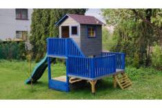 Drewniany domek dla dzieci zbudowany na dwupoziomowej platformie, pomalowany na mocne ale spokoj ...
