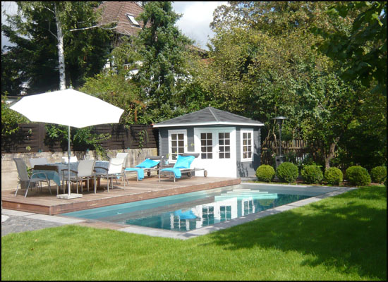 Drewniany domek Belgia postawiony w rogu ogrodu z basenem idealnie spełnia funkcję przebieralni. ...