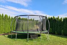 Wyjątkowo duża trampolina ogrodowa ustawiona w zielonym kącie ogrodu. Dzięki siatce bezpieczeńst ...